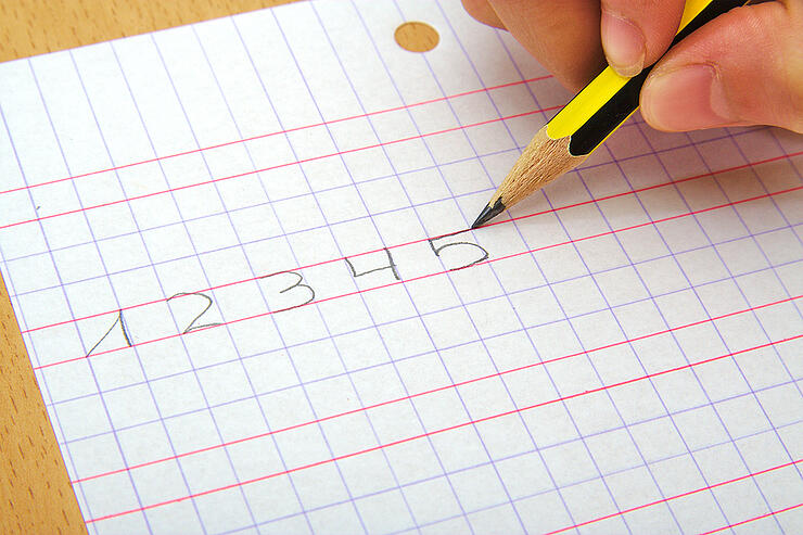 Closeup on the hand of a child writting numbers from one to five