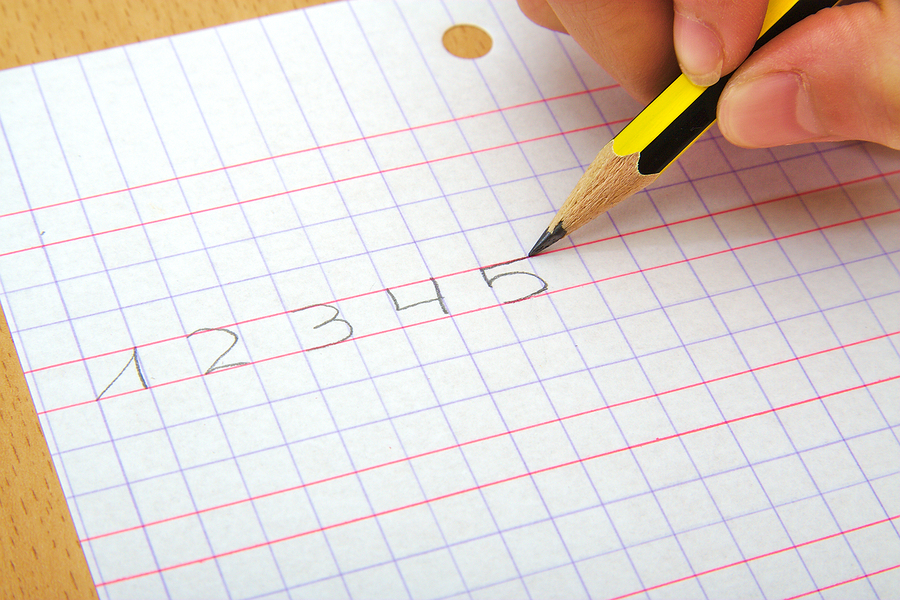 Closeup on the hand of a child writting numbers from one to five