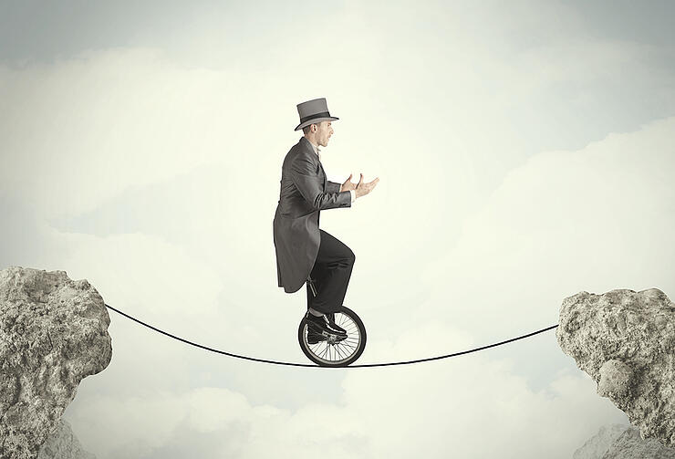 Brave business man riding an mono cycle between cliffs concept