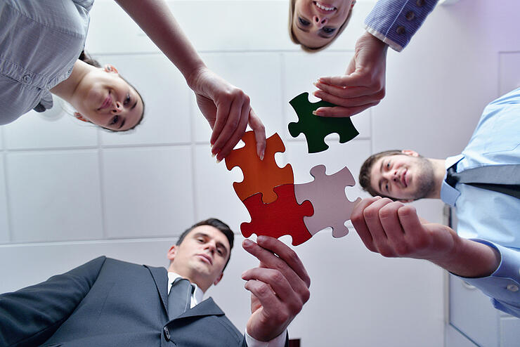 Group of business people assembling jigsaw puzzle and represent